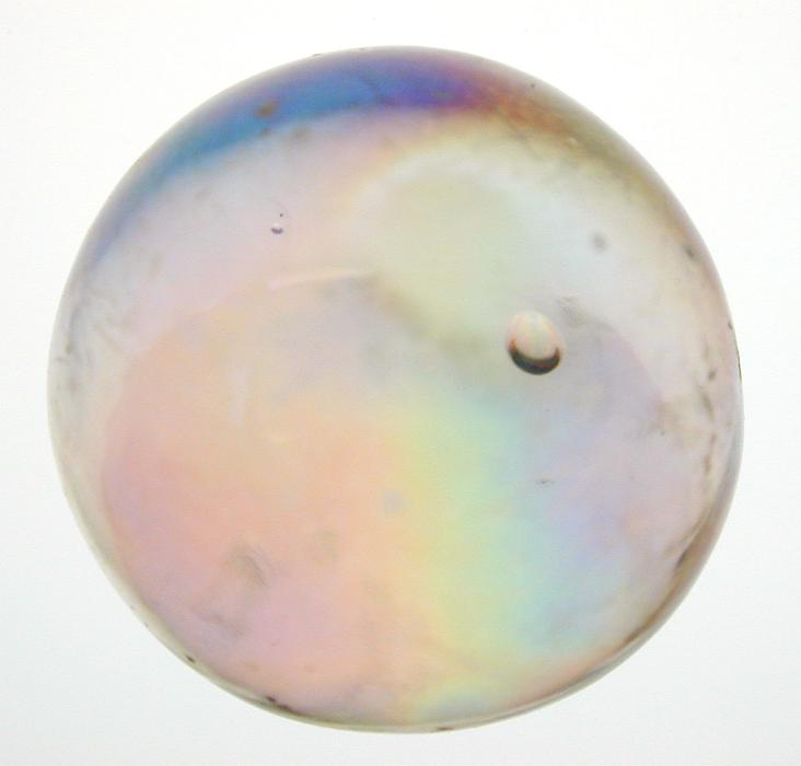 Free Stock Photo: Iridescent toy glass marble viewed close up showing the colorful internal refraction of light over white
