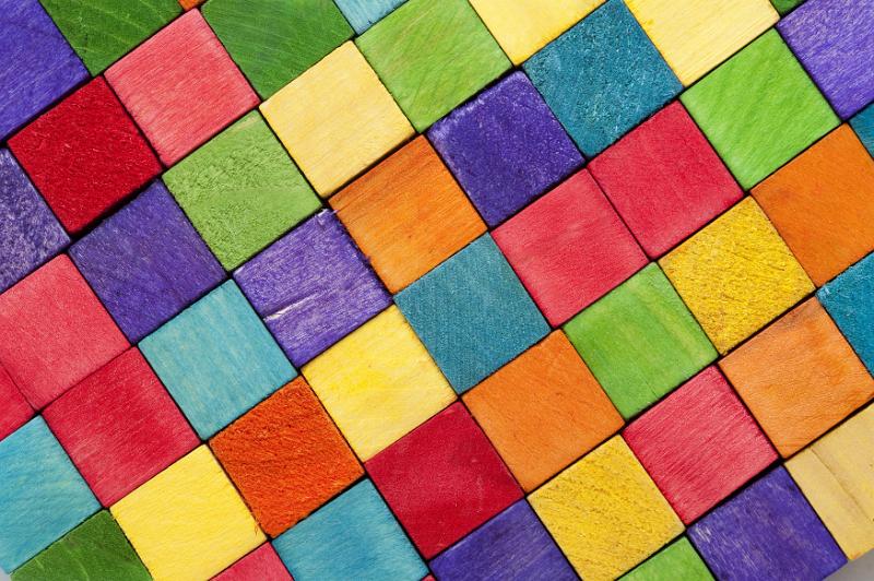 Free Stock Photo: Vibrant background pattern of wooden toy blocks in the colors of the rainbow arranged in rows to form a diamond pattern in a full frame view