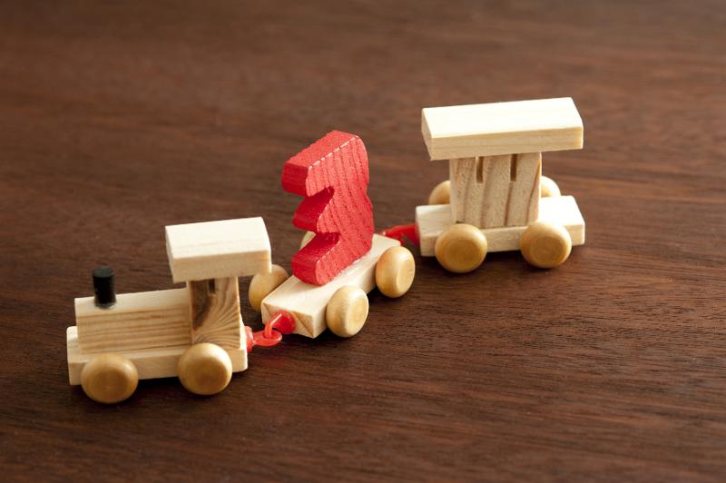 Free Stock Photo: Wooden toy train with the number three in colorful red mounted on a carriage pulled by an engine and wagon for teaching kids counting and arithmetic