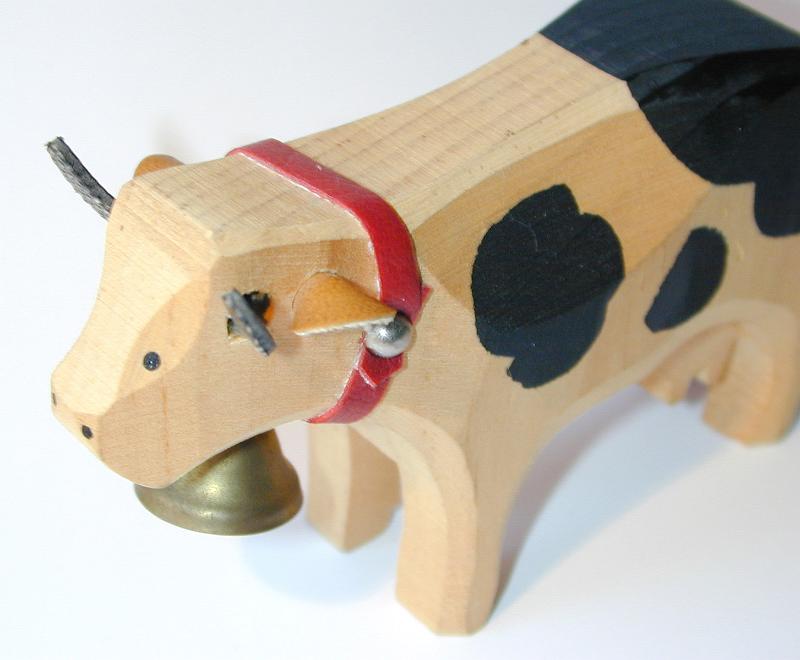 Free Stock Photo: Wooden toy cow with a brass bell on a red band around its neck and leather ears viewed close up high angle