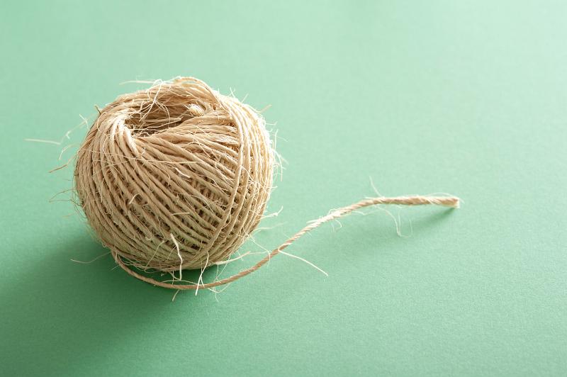 Free Stock Photo: Small clew of jute threads of natural linen or ball of rustic strings viewed in close-up on pale green background