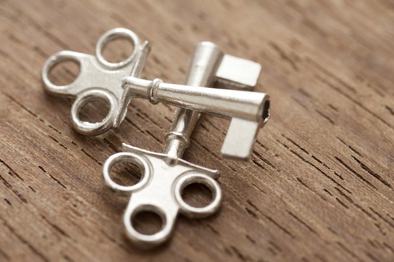 Free Stock Photo: Two decorative small silver crossed cabinet keys lying on a wooden surface in a conceptual image