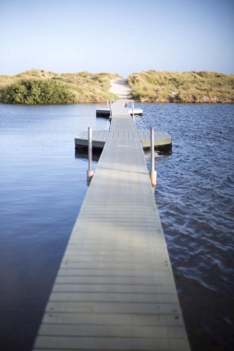 Free Stock Photo: Long wooden boardwalk bridge over the water of a lake stretching straight ahead in a concept of crossing bridges