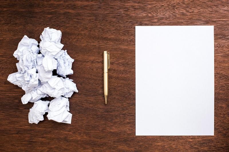Free Stock Photo: Difficult search for the right idea concept with a bunch of crumpled papers and a clean sheet of paper and a pen on wooden table surface, viewed from above
