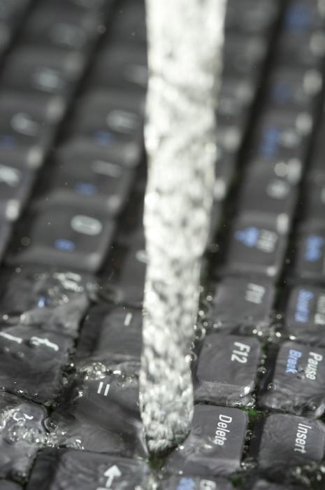 Free Stock Photo: Streaming data concept with pouring water over a black computer keyboard in a full frame vertical view