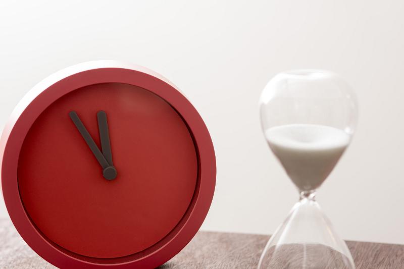 Free Stock Photo: Deadline or countdown concept with egg timer or hour glass and colorful red modern clock in a close up view