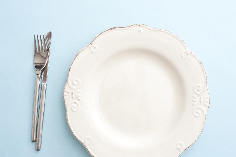Free Stock Photo: Clean empty white dinner plate on a table with cutlery alongside viewed from overhead in a food and catering concept