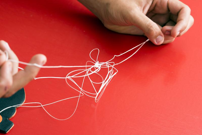 Free Stock Photo: Fixing a problem concept by untangling a knot with a closeup view of hands of a man unravelling a badly knotted piece of string over a red background