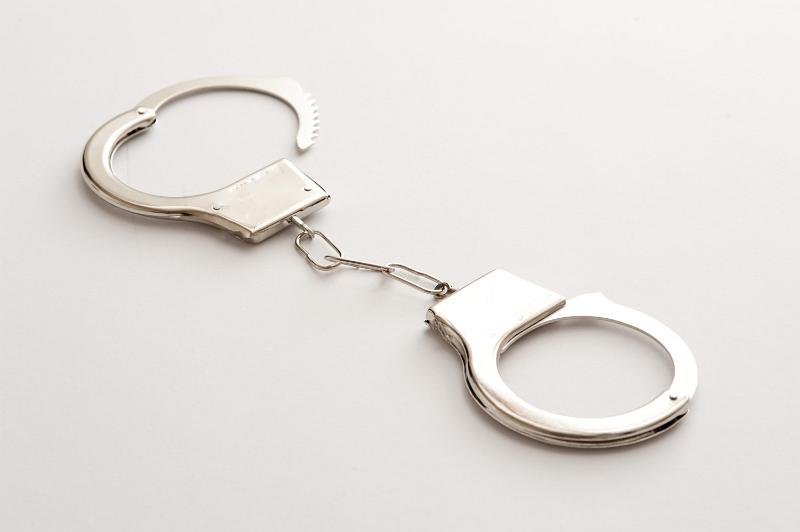 Free Stock Photo: Pair of unlocked metal handcuffs lying diagonally on white in a conceptual image of law and order, captivity and freedom