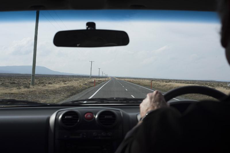 Free Stock Photo: Long journey ahead concept with man driving a car in an over the shoulder perspective looking at the long road stretching into the distance through the windscreen