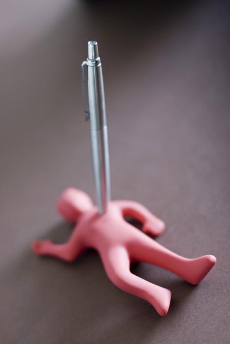 Free Stock Photo: Management trouble concept with small pink figure stabbed through the heart with a pen lying prone on grey with copy space