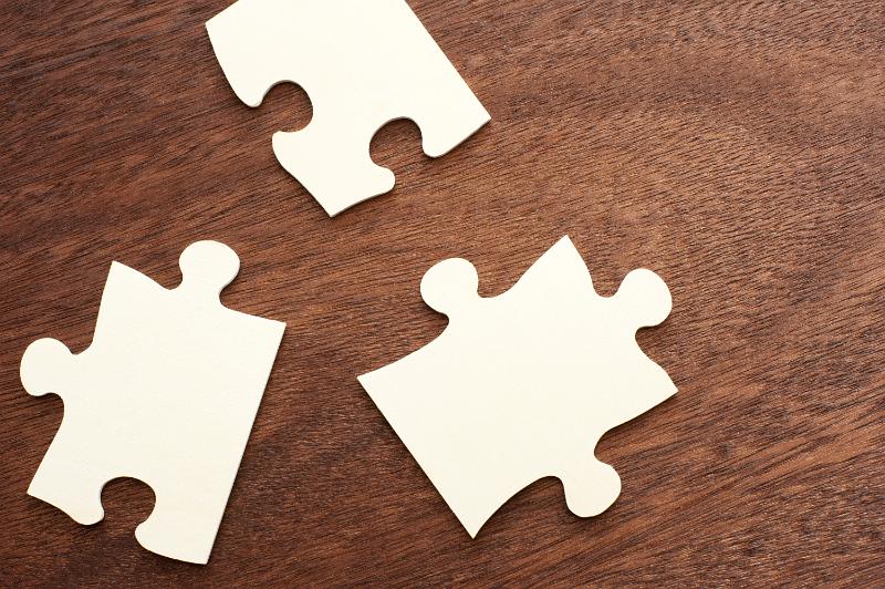 Free Stock Photo: Three loose puzzle pieces lying on a wooden table with copy space in a concept of problem solving and answers