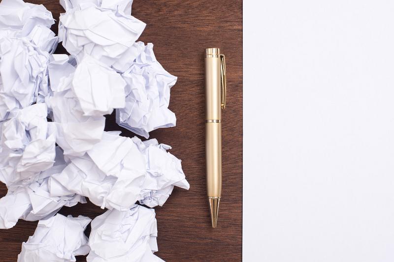Free Stock Photo: Tough work or business idea concept with a pile of crumpled discarded white paper alongside a pen on a desk and clean page of paper alongside