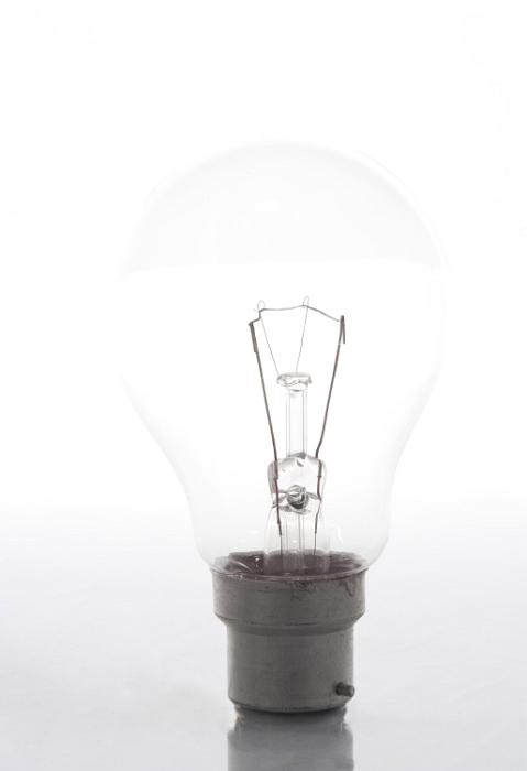 Free Stock Photo: Incandescent lightbulb with bayonet mount socket type placed vertically on glossy surface against white background