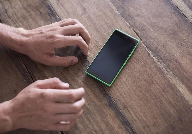 Free Stock Photo: Stressed waiting for message or FOMA - fear of missing out concept. Persons hands impatiently reaching mobile phone with black screen, sitting on wooden table surface, viewed from above