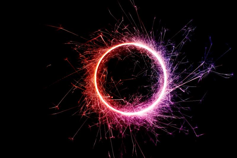Free Stock Photo: a spinning catherine wheel with a red purple tinted erruption sparks of light