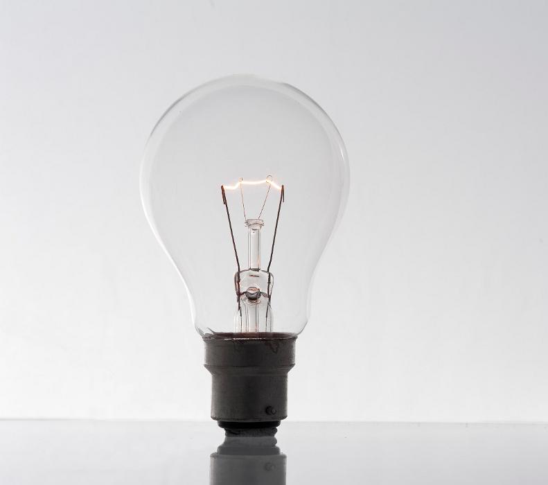Free Stock Photo: conceptual image of a glowing lightbulb stood alone on a light background and reflective surface