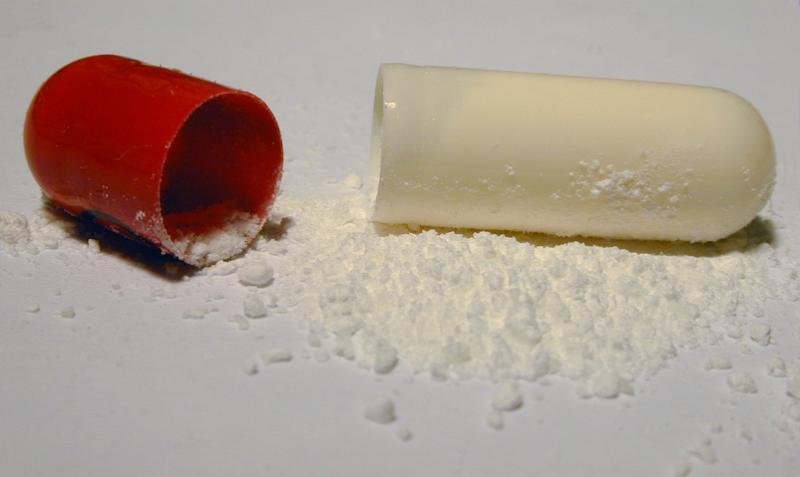 Free Stock Photo: Close Up of Broken Open Red and White Pill Capsule on White Background with White Medication Powder Spilled Out