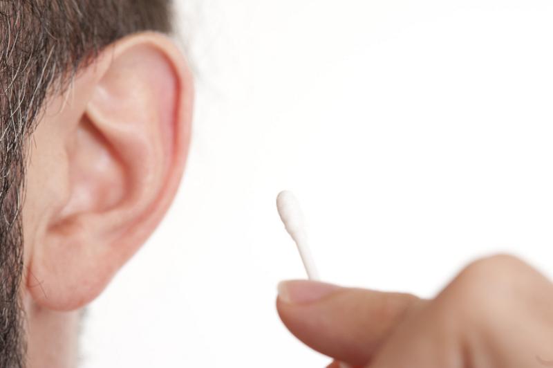 Free Stock Photo: a man holding a cotton bud with his ear out of focus in the background