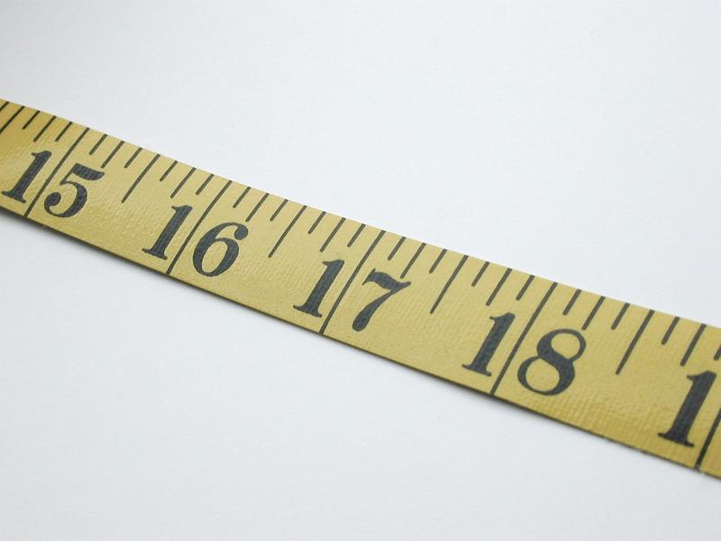 Free Stock Photo: Close Up of Yellow Tape Measure Angled Across White Background, Used in Textile and Construction Industry