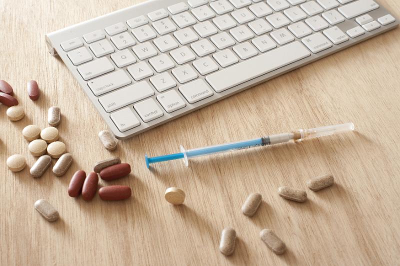 Free Stock Photo: medical analysis concept, a syringe, and some tablets with a computer keyboard on wooden desk