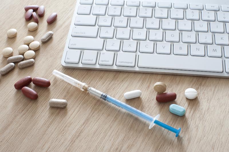 Free Stock Photo: Modern medicine concept with a computer keyboard for online ordering and research surrounded by assorted tablets and a syringe