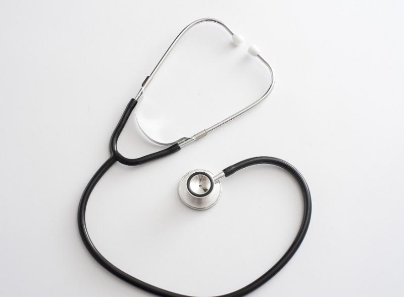Free Stock Photo: Doctors stethoscope for listening to heart and body sounds in a patient lying coiled on white viewed from above with copy space