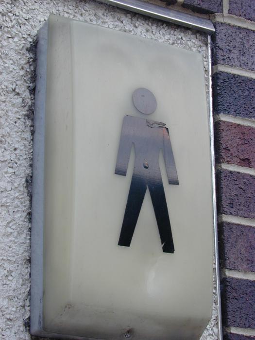 Free Stock Photo: Gents public toilet sign with the silhouette of a man on a light unit mounted on an external wall of an outdoor ablution block offered as a service to the public