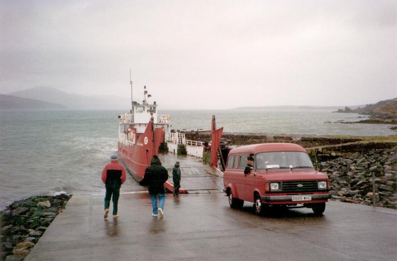Free Stock Photo: Car disembarking from a ferry onto dry land on a wet rainy day at the coast with people standing around watching