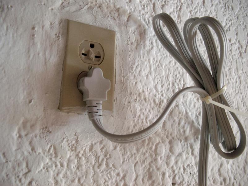 Free Stock Photo: Domestic wall mounted electrical socket with an attached plug and cable supplying household electricity