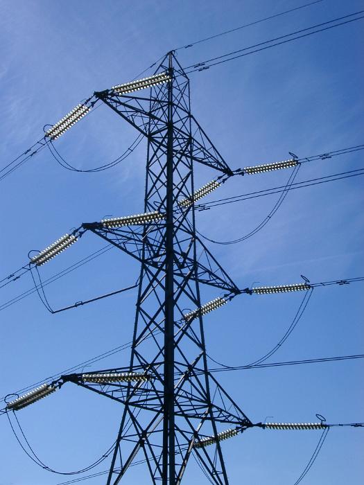 Free Stock Photo: Detail of the top of an electricity pylon, showing all the connecting cables, against a clear blue sky