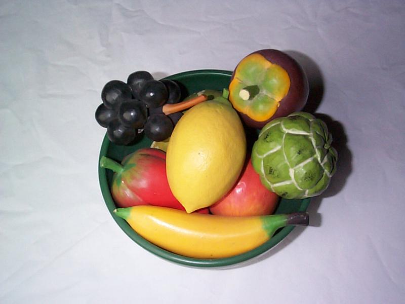 Free Stock Photo: Bowl of fake fresh fruit with colorful wooden imitations viewed from overhead over a grey background