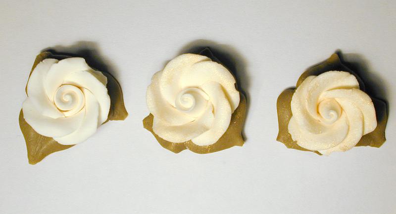 Free Stock Photo: Three icing sugar roses for decorating cakes and confectionery viewed from overhead in a row on a grey background