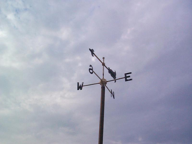 Free Stock Photo: Weathervane against a cloudy sky with the arrow pointing towards the south showing the direction of the wind, with copyspace