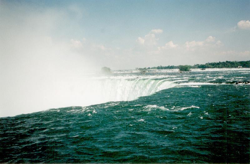 Free Stock Photo: Niagara Falls looking from above as the water plunges over the cliff viewed looking over the fast flowing water with the spray and mist in the background in a travel and tourism concept