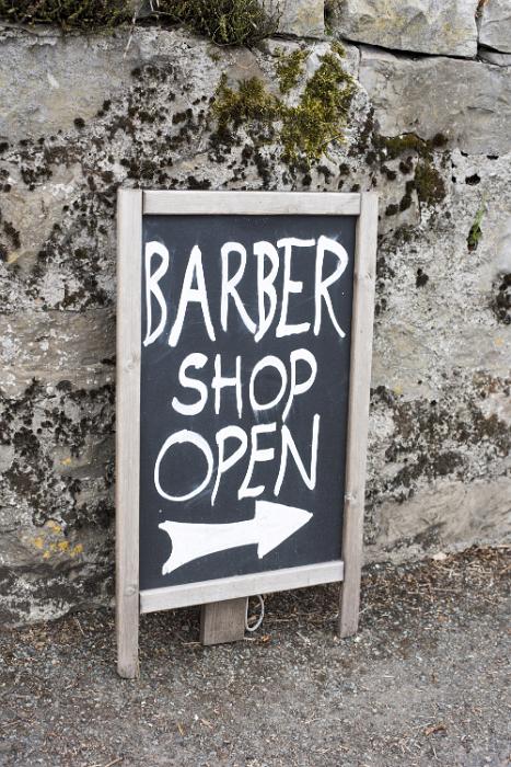 Free Stock Photo: Handwritten sign - barber Shop Open with arrow standing in front of a concrete exterior retaining wall