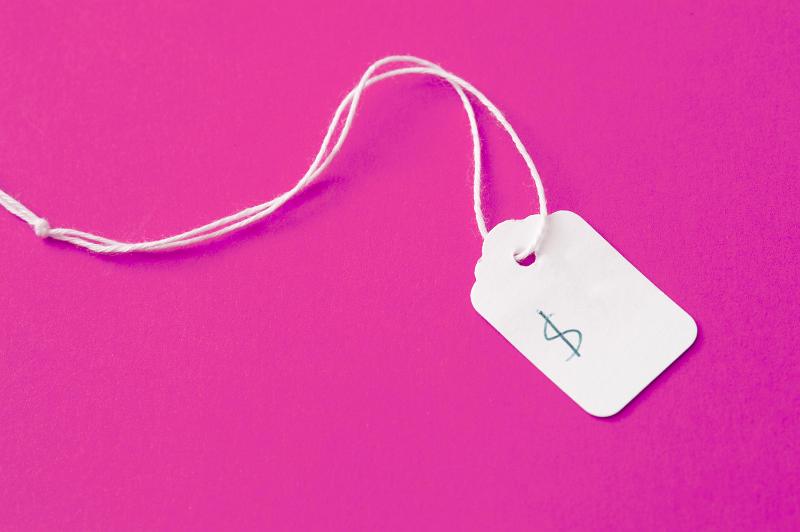 Free Stock Photo: White cardboard price label or tag with string and a handwritten dollar sign lying on a bright pink background with copy space