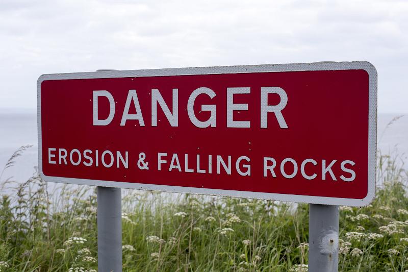 Free Stock Photo: Erosion and falling rocks danger sign with white letters on red well visible background, installed outdoors near the sea