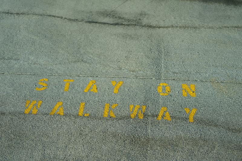 Free Stock Photo: Stencilled street sign - Stay On Walkway - painted in yellow on the asphalt viewed from overhead