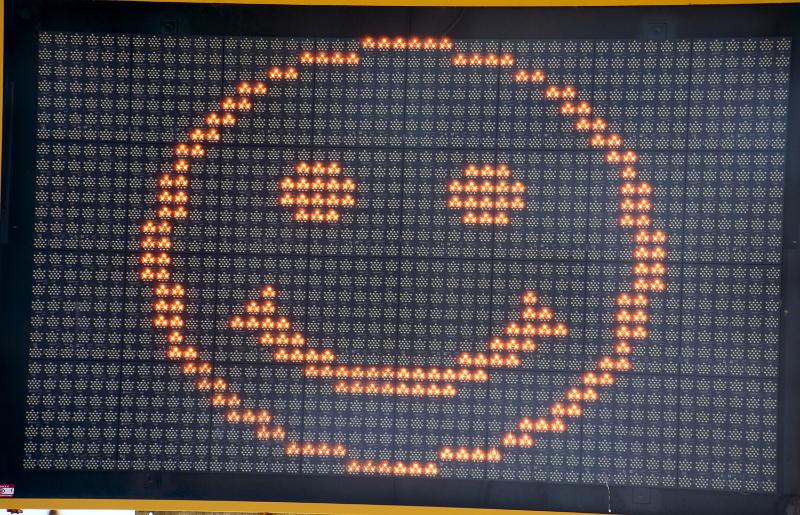 Free Stock Photo: Emoticon of a happy smiling face in orange on an electronic sign in a close up full frame view