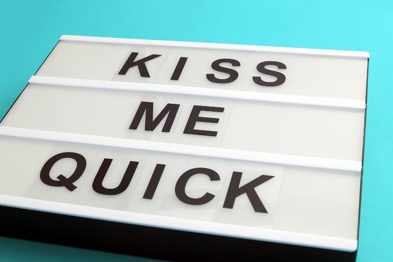 Free Stock Photo: Kiss Me Quick sign with black letters on white box, viewed in close-up and placed on cyan background