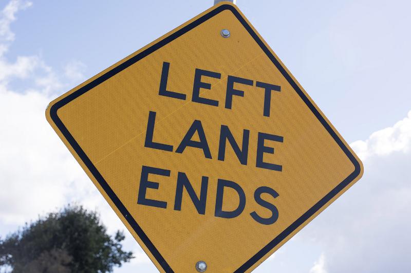 Free Stock Photo: Yellow traffic warning sign - Left Lane Ends - in a close up view against a cloudy sky