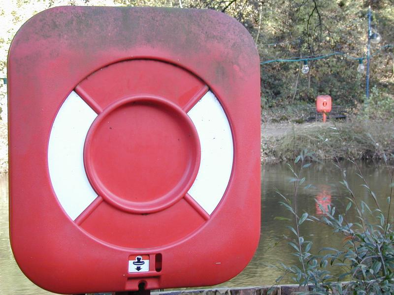 Free Stock Photo: Red and white life buoy or flotation aid mounted on an exterior wall ready for use in emergencies