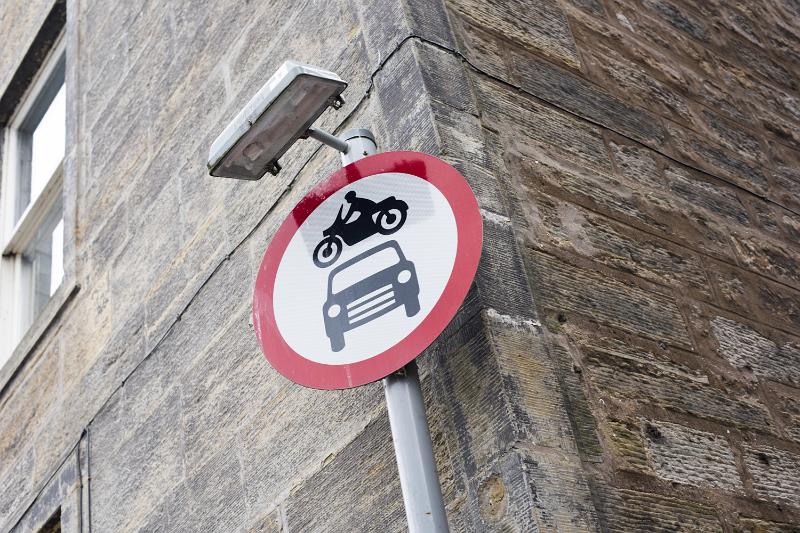 Free Stock Photo: No vehicles beyond this point warning sign with light above on a pole at the corner of a building