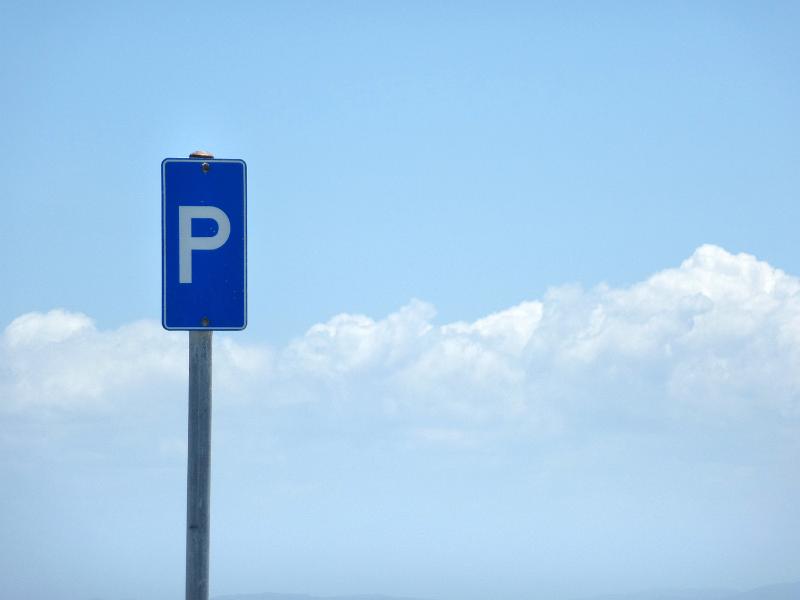 Free Stock Photo: Blue parking sign on a tall pole against a cloudy blue sky with copy space