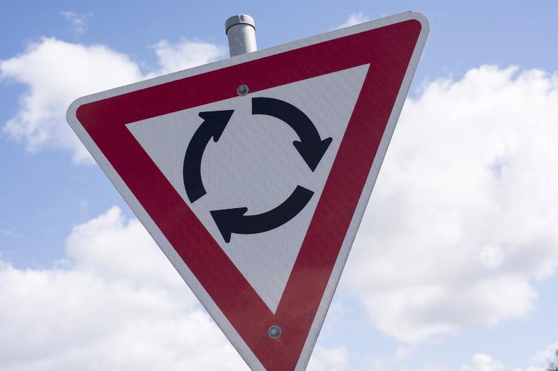 Free Stock Photo: Warning sign for an approaching traffic roundabout in a red triangle against a cloudy blue sky