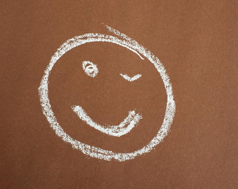 Free Stock Photo: Smiley face with a wink hand drawn in chalk on a brown background