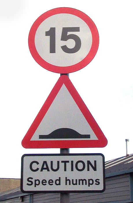 Free Stock Photo: Road sign for speed humps and 15 speed limit viewed in close-up from low angle against grey sky