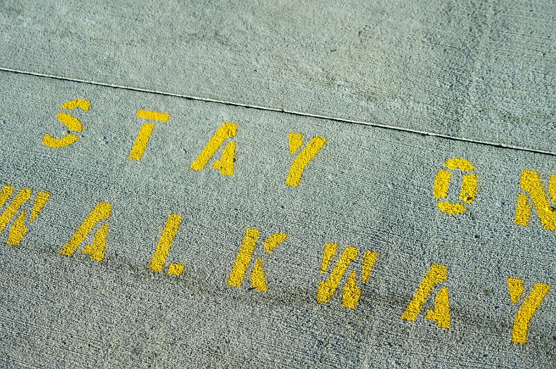 Free Stock Photo: Stay on Walkway street sign stencilled on a road surface in yellow paint as a warning to pedestrians