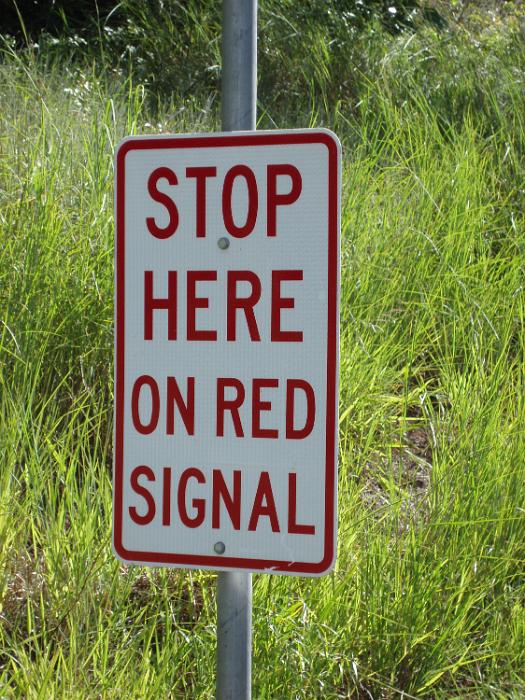 Free Stock Photo: Warning Stop Sign to stop on the red signal against a grassy verge on a road in an oblique angle view